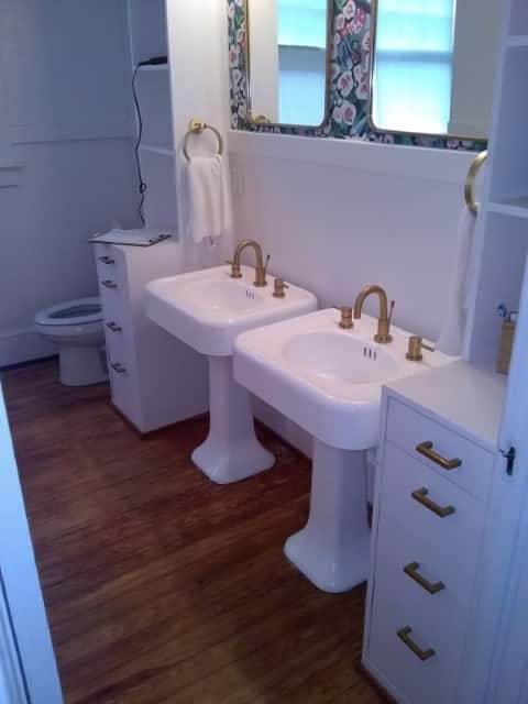 New installation of twin pedestal sinks with brass faucets.